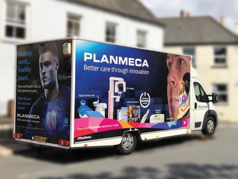 A planmeca van driving on a road