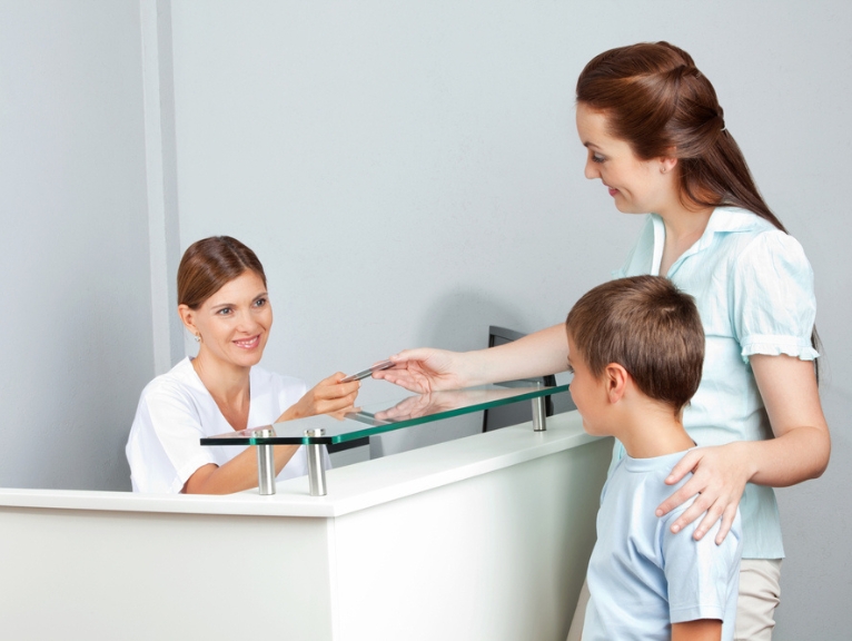 a child being greeted by a friendly receptionist at a dental practice
