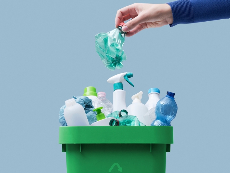 Someone placing items into a recycling bin.