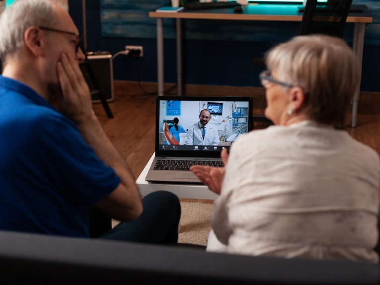 A couple has a teledentistry appointment on a laptop