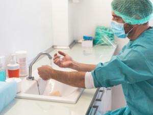 A dentist washes hands at a sink