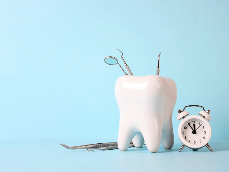 dental patient behaviour: Tooth model with dental tools and a clock representing treatment planning and patient behaviour