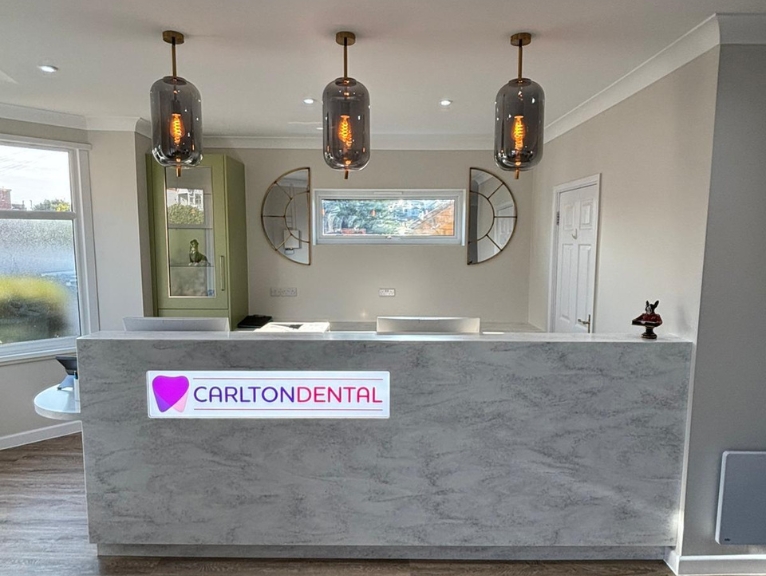 Dental Brand Identity: Modern dental reception desk with illuminated Carlton Dental logo and contemporary lighting.