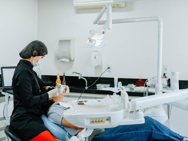 Dental equipment for practice A dentist in a black uniform and mask examines a patient using dental equipment in a treatment room.